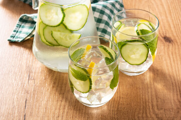Sassy water or water with cucumber and lemon on wooden table	