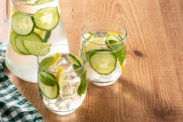 Sassy water or water with cucumber and lemon on wooden table	