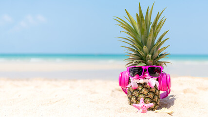 Summer in the party.  Hipster Pineapple Fashion in sunglass and listen music on the sand beach...
