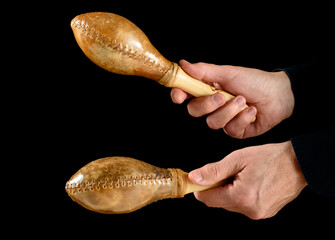 hands playing cuban maracas on black background