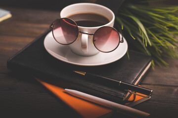 glasses notepads the office handle a cup of coffee saucer wooden table
