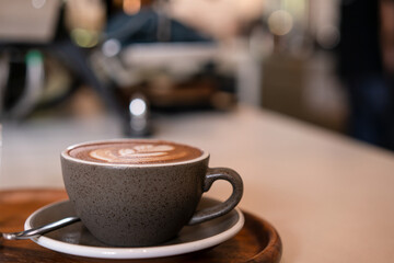 Hot coffee with milk foam on wooden table at coffee shop