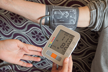 Monitoring blood pressure of patients using upper arm blood pressure monitor in the clinic examination room.