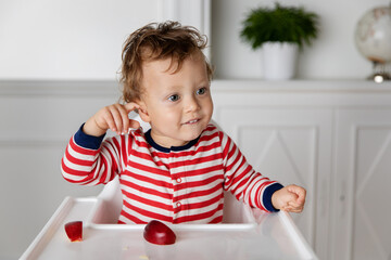 Baby in high chair touching his ear with his finger