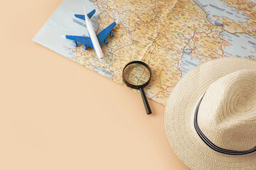 Straw hat, map, plane and magnifying glass on pastel background. Summer holiday, vacation, travel concept. Flat lay, top view, copy space.