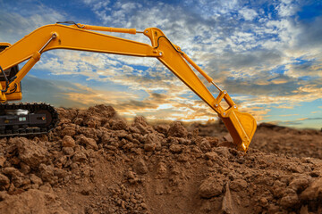 Arm and bucket of excavators are digging the soil in the construction site on the sky and cloud...
