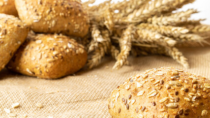 Home baked bread. Rye bakery with crusty loaves and crumbs. Fresh rustic traditional bread with wheat grain ear or spike plant on natural cotton background. Design element for bakery product label.