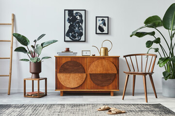 Stylish scandinavian composition of living room with design commode, black mock up poster frames, chair, wooden stool, book, decoration, plants and personal accessories in modern home decor.