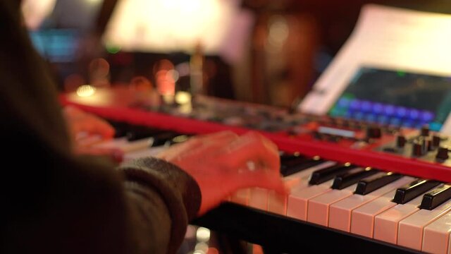 A pianist and a drummer perform modern music at a party. Men in black perform jazz, soul, chill out songs at nightclub. Musicians play instruments under muffled lighting, close-up. Relaxing atmosphere