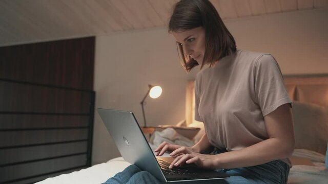 Young woman sitting in bad posture and using laptop on bed