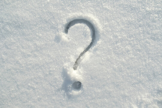 Punctuation question mark drawn on the fresh snow on a sunny winter day. 