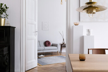 Stylish scandi interior of home space with design grey sofa, retro wooden table, mock up poster frame, decoration , carpet and personal accessories in elegant home decor.