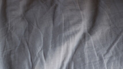 wrinkled cotton fabric lying on a flat surface with textured drapery, graphic resource with empty space, light gray fabric with folds, shadows and stripes texture, light and minimalistic backdrop