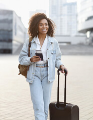 Woman tourist with suitcase luggage holding passport and tickets. Smiling mixed race girl portrait...