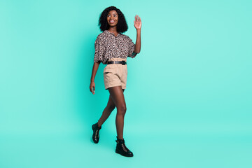 Photo of cheerful lady go wave hand look empty space wear leopard print shirt shorts isolated teal color background