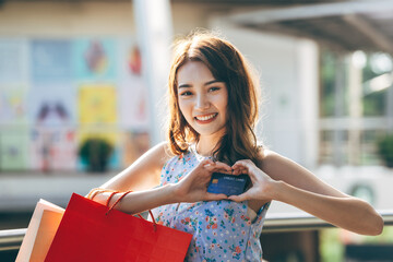  Young adult asian woman holding credit card and shopping bags.