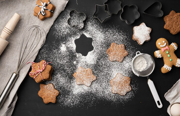 baked star-shaped gingerbread cookie sprinkled with powdered sugar on a black table and ingredients