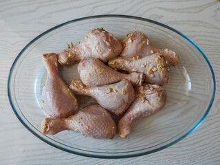 chicken legs marinated with garlic in a glass bowl