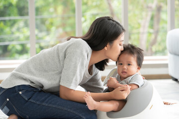 Young beautiful asian mother lifting and playing with her baby.