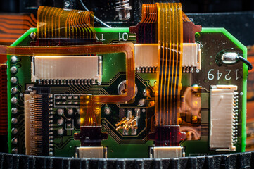 Board with a microchip and connected and a ribbon cable inside the lens close-up, macro photography