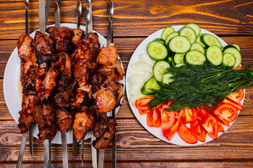 Barbecue grilled meat skewers fried on fire, strung on metal sticks on a plate on the table for ready meals.