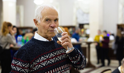 Elderly man drinking champagne in cafeteria of theater