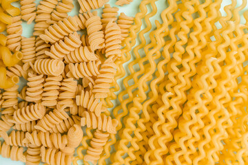Different types of pasta from wheat varieties laid out in a line on a light wine background, copy space on banner