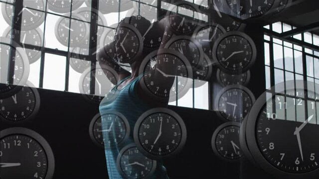 Multiple ticking clocks falling against african american woman taking a break from working out