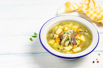 Canned fish soup in a bowl on wooden background. Space for text.