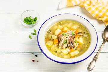 Spicy homemade fish soup in a bowl on wooden background. Space for text.