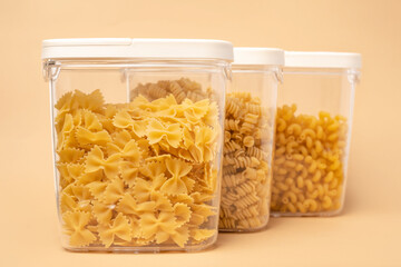 Different types of pasta in containers on a beige background