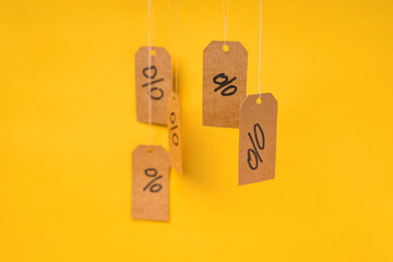 Tags with drawn percentages hang on strings on a yellow background, concept of discounts and sales
