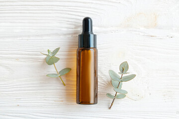 Brown transparent bottle with 100% pure hyaluronic acid serum for skin vaccination and dropping on wood textured table background. Close up, copy space, top view.