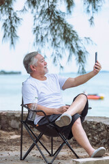 Fototapeta premium senior elder take vdo call with mobile, he is very happy and smile in outdoor background.