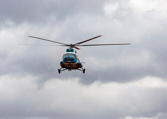 Fototapeta na wymiar Helicopter is landing on the background of dark rain clouds.