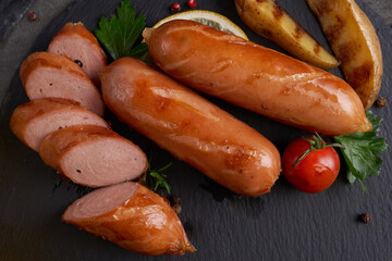 sausages and ingredients for cooking. Grilled sausage with the addition of herbs and and spices, vegetables, rosemary, thyme on the grill plate, Grilling food, bbq, barbecue, on stone table. Top view.