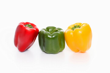 Three bell peppers, red, green and yellow on white background,