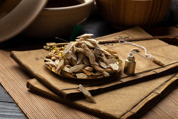 Astragalus membranaceus，Ancient Chinese medicine books and herbs on the table.English translation：Emperor's Internal Classic