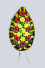 Wreath with artificial flowers for tombstone on gray background