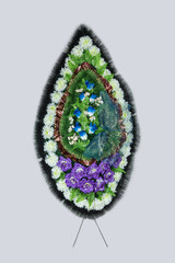 Wreath with artificial flowers for tombstone on gray background