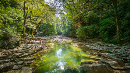 Obraz premium Adventurous peoples is standing on sharp stones and enjoying the beautiful view of wild rainforest landscape