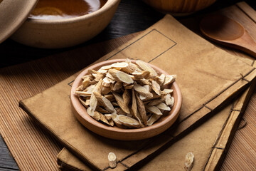 Astragalus membranaceus，Ancient Chinese medicine books and herbs on the table.English...