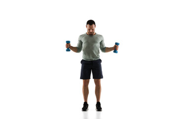 Dumbbells. Young caucasian male model in action, motion on white background with copyspace. Concept of sport, movement, energy and dynamic, healthy lifestyle. Training, practicing. Authentic.