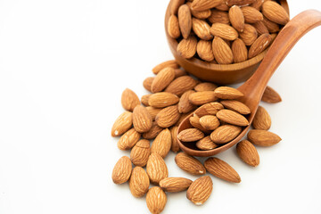 almond in a wooden spoon and bowl on white background. (selective focus; close-up shot)
