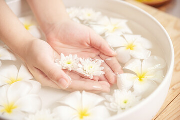 Obraz na płótnie Canvas Spa treatment and product for female feet and hand spa. white flowers in ceramic bowl with water for aroma therapy at spa.