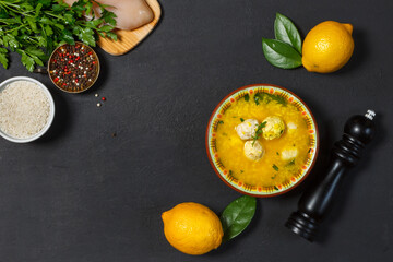 Avgolemono chicken soup, with egg yolks, lemons and rice. Top view on a black background with ingredients. Copy of the space