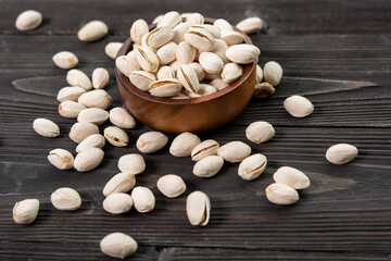 Bowl with pistachios on a wooden table. (selective focus; close-up shot)