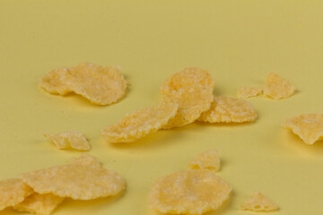 Pile of yellow cornflakes on yellow  background