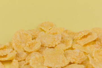 Pile of yellow cornflakes on yellow  background
