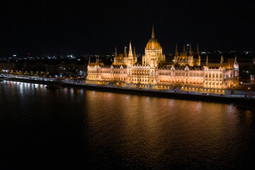 Fototapeta na wymiar Aerial view of illuminated Budapest Parliament building at night with dark sky and reflection in Danube river. Panoramic view of hungarian Parliament building. Budapest, Hungary at night.